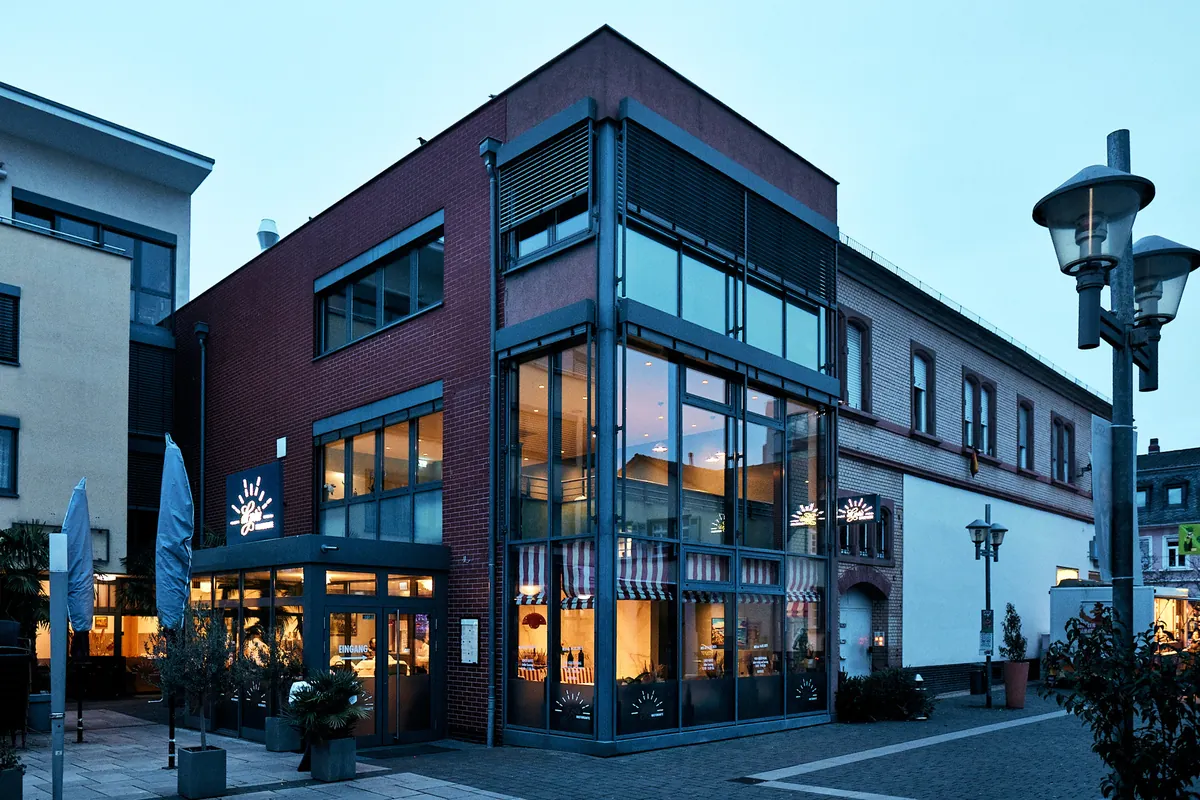 Vorher: Restaurant-Fassade zur blauen Stunde mit verhüllten Sonnenschirmen