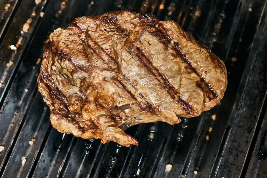 Vorher: dunkles Foto eines Steaks auf dem Grillrost